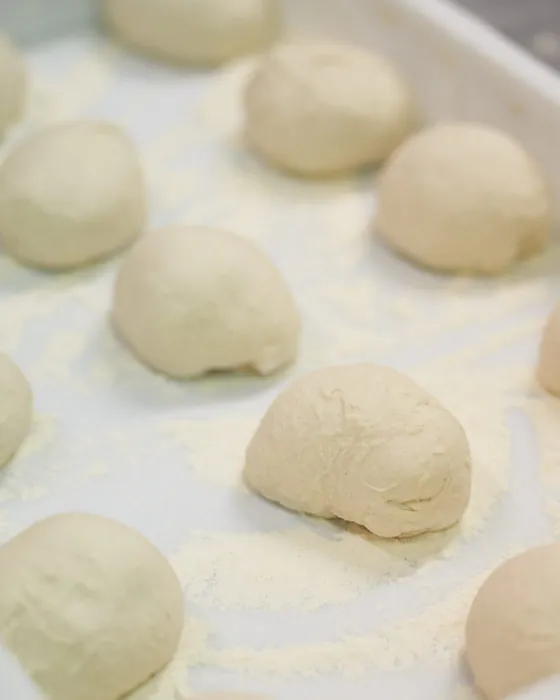 Panetti di pizza che lievitano su un piano infarinato