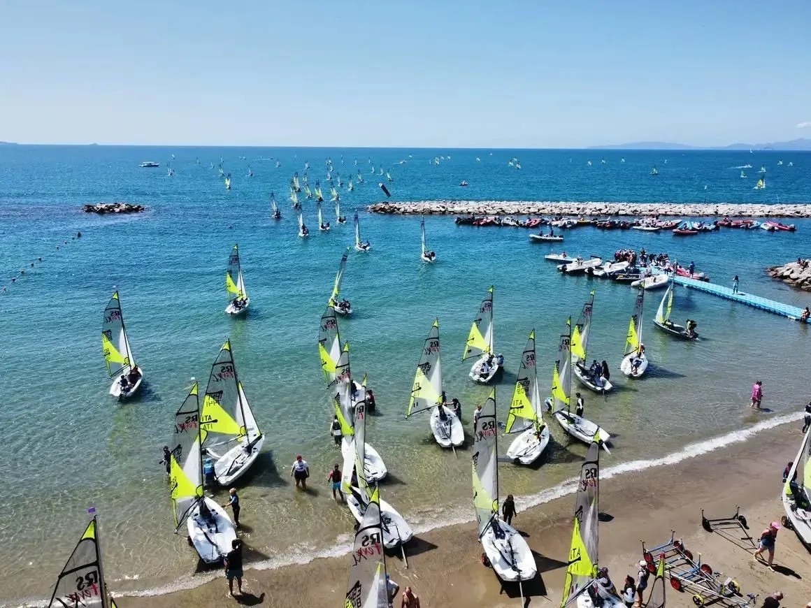 Decine di derive con le vele gialle in mare davanti alla spiaggia di Follonica, viste dall'alto