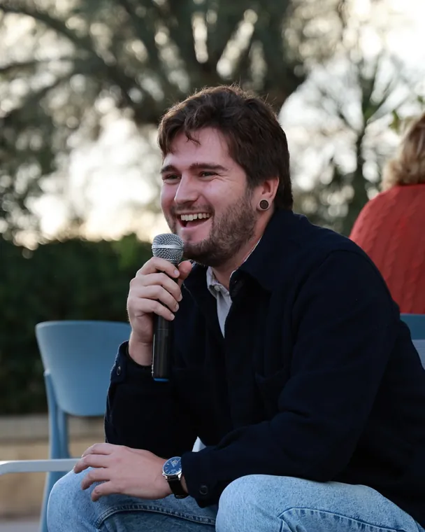 Maciej Vella smiling while speaking into a microphone