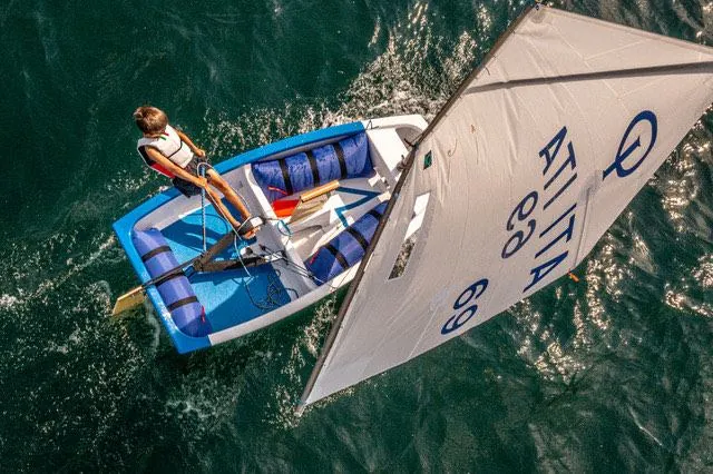 Una deriva in regata vista dall'alto, con la vela bianca e lo scafo azzurro