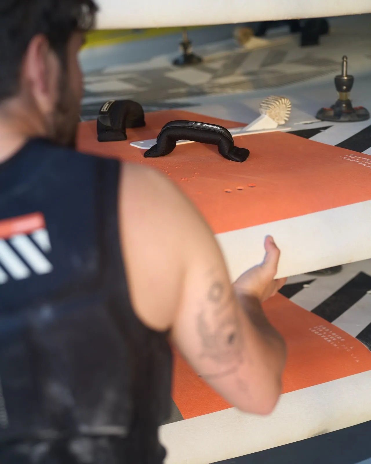 Un istruttore prende una tavola da SUP dalla rastrelliera del campeggio